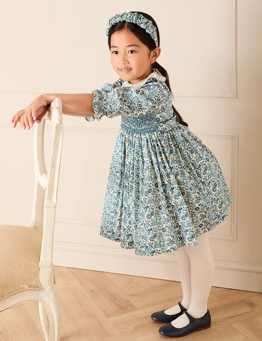 Daphne Floral Hand Smocked Frill Collar Long Sleeve Dress in Blue (18mths-10yrs) Dresses from Pepa London